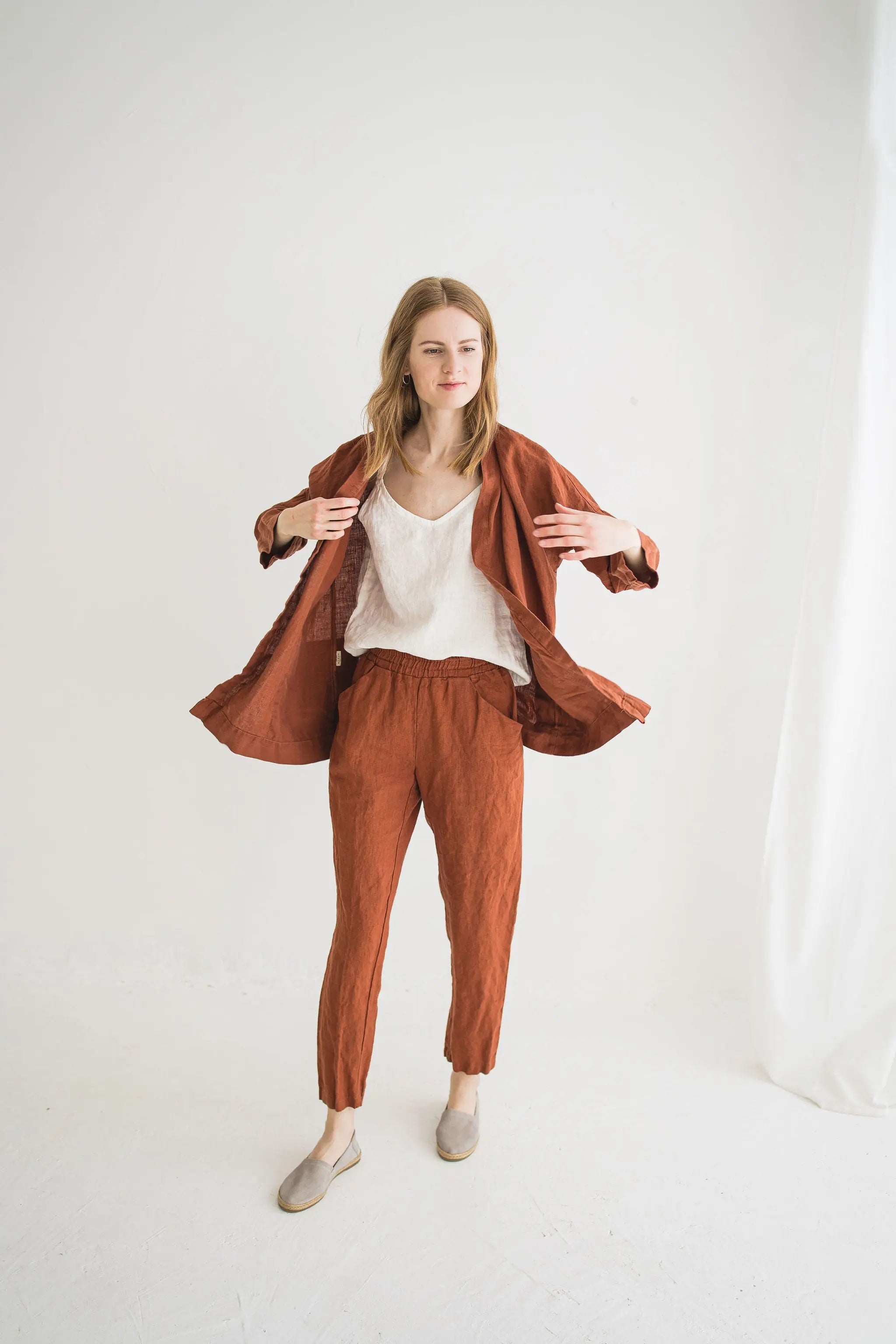 Woman wearing a rust-colored jacket and pants on a white background