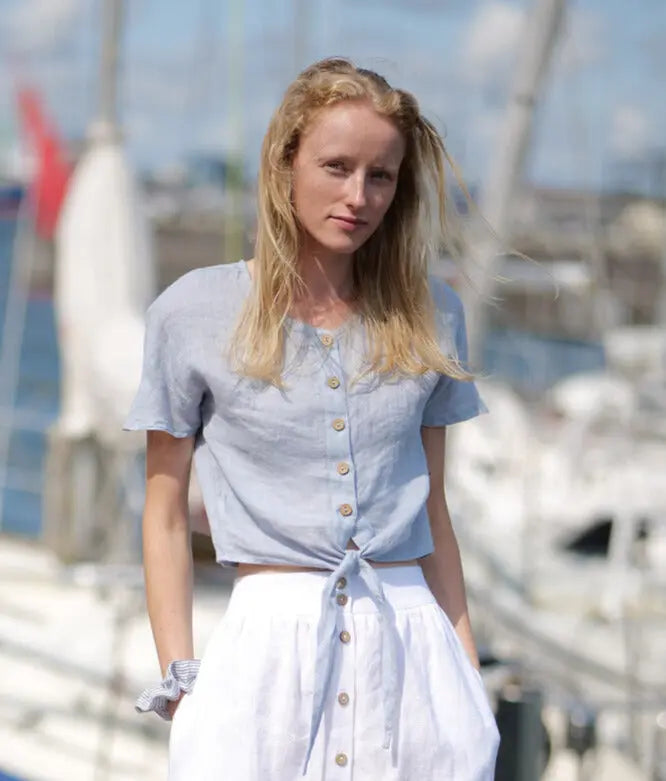 Woman wearing light blue linen blouse and white midi skirt by marina.