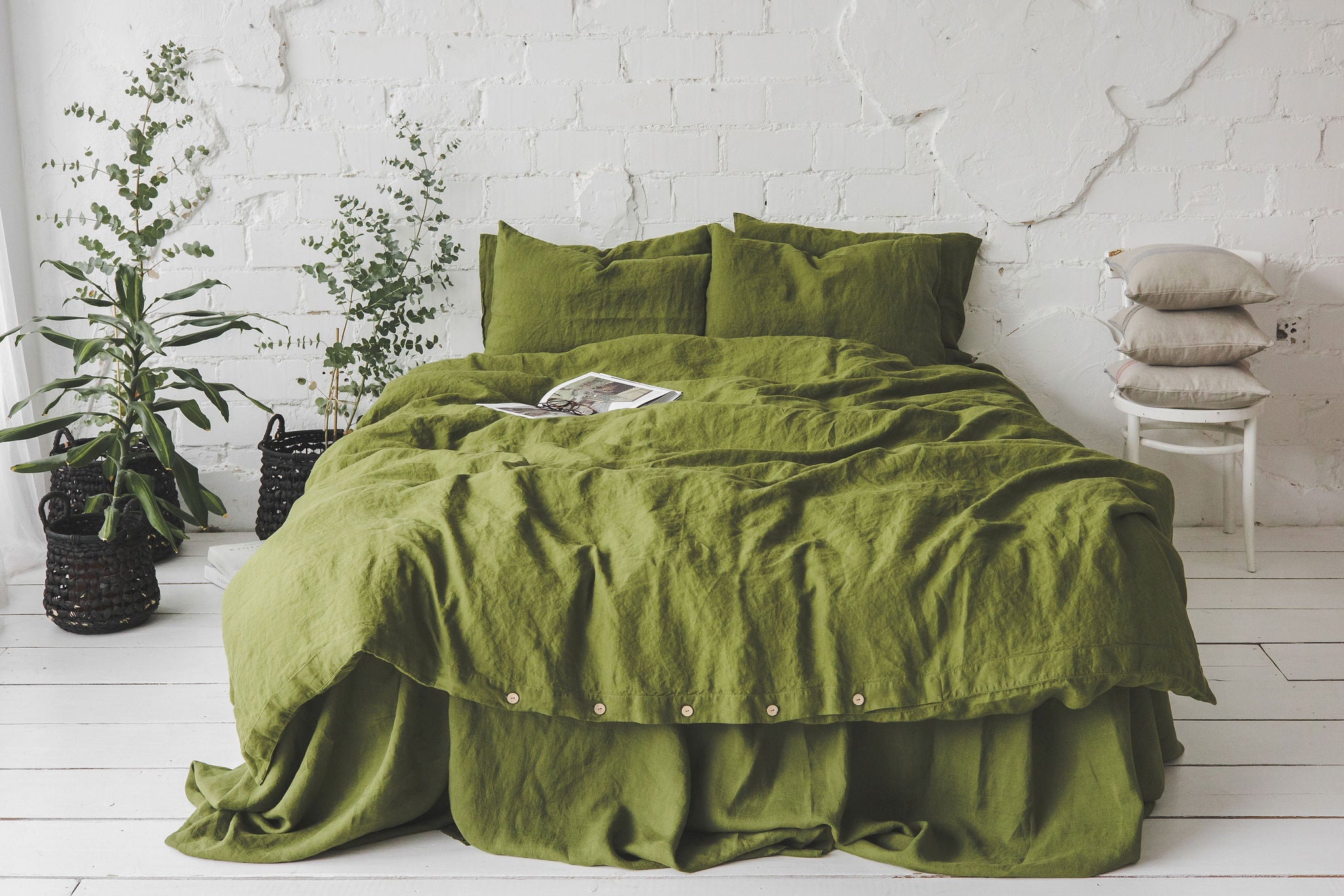 beautifully made bed with a matching linen bedding set all in a rich green moss color