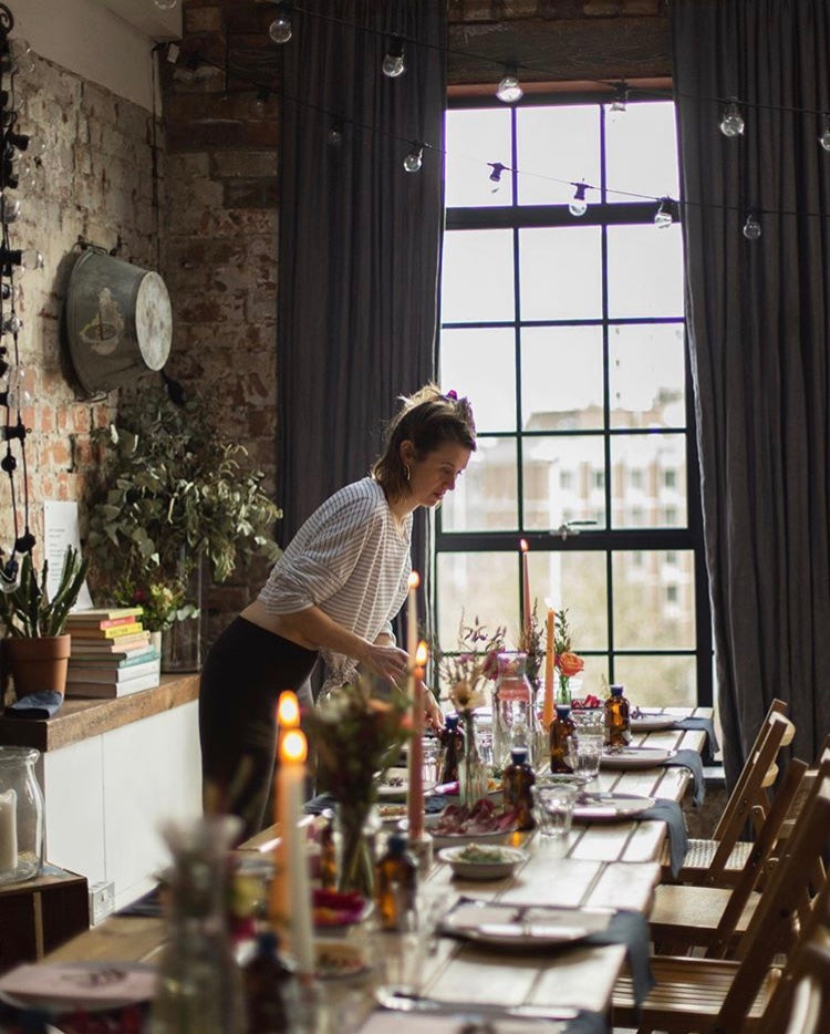 Women setting table for candlit dinner event. Wholesale linen napkins, quality linen tablecloths, linen curtains bulk, linen cushion covers, durable linen placemats, high-quality linen runners, linen aprons wholesale, soft linen towels, eco-friendly linen products, custom linen items