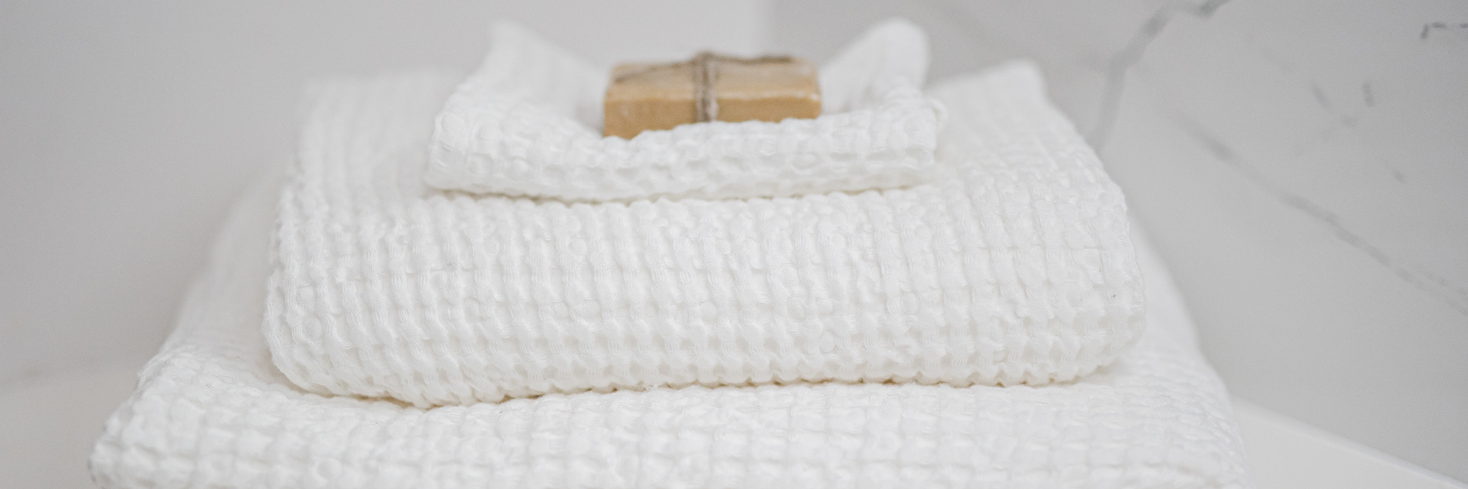 A stack of white linen bath towels in a waffle pattern