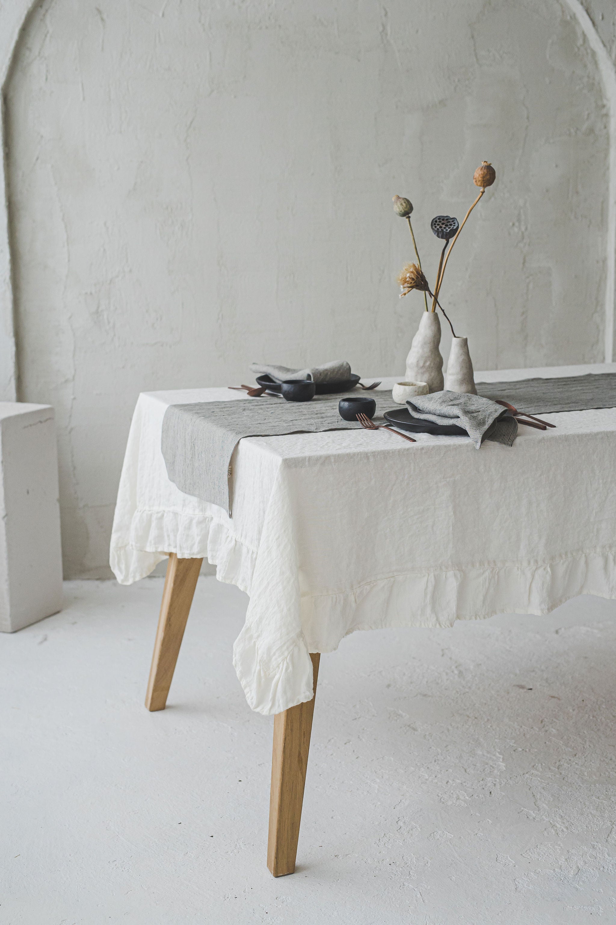 a set up table with white linen tablecloth, striped linen runner and striped linen napkins on the plates