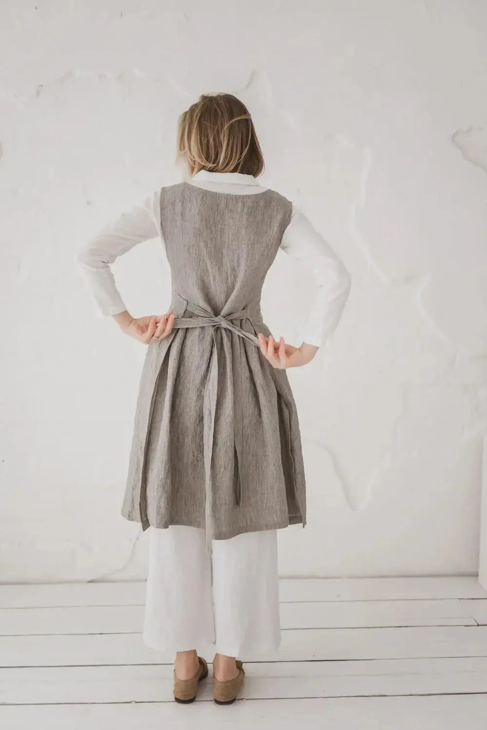 Woman tying back bow of Convertible Linen Pinafore Dress - Epic Linen