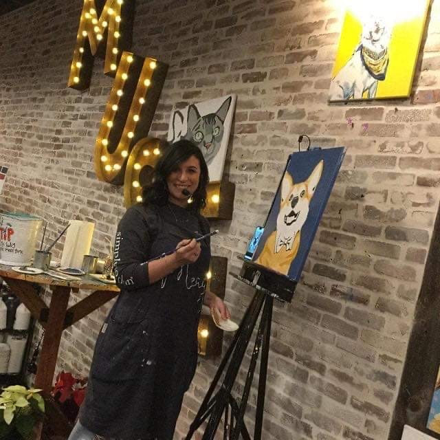 A woman wearing an Epic Linen pinafore apron in an art studio.