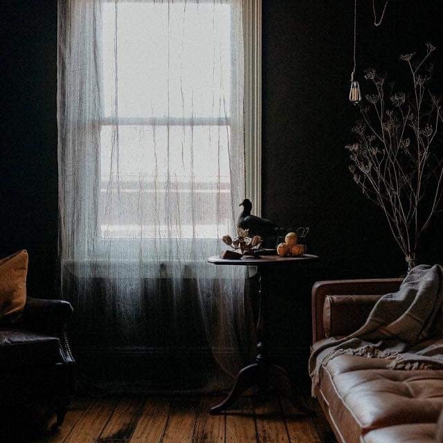 A living room with linen curtains draping over a window.