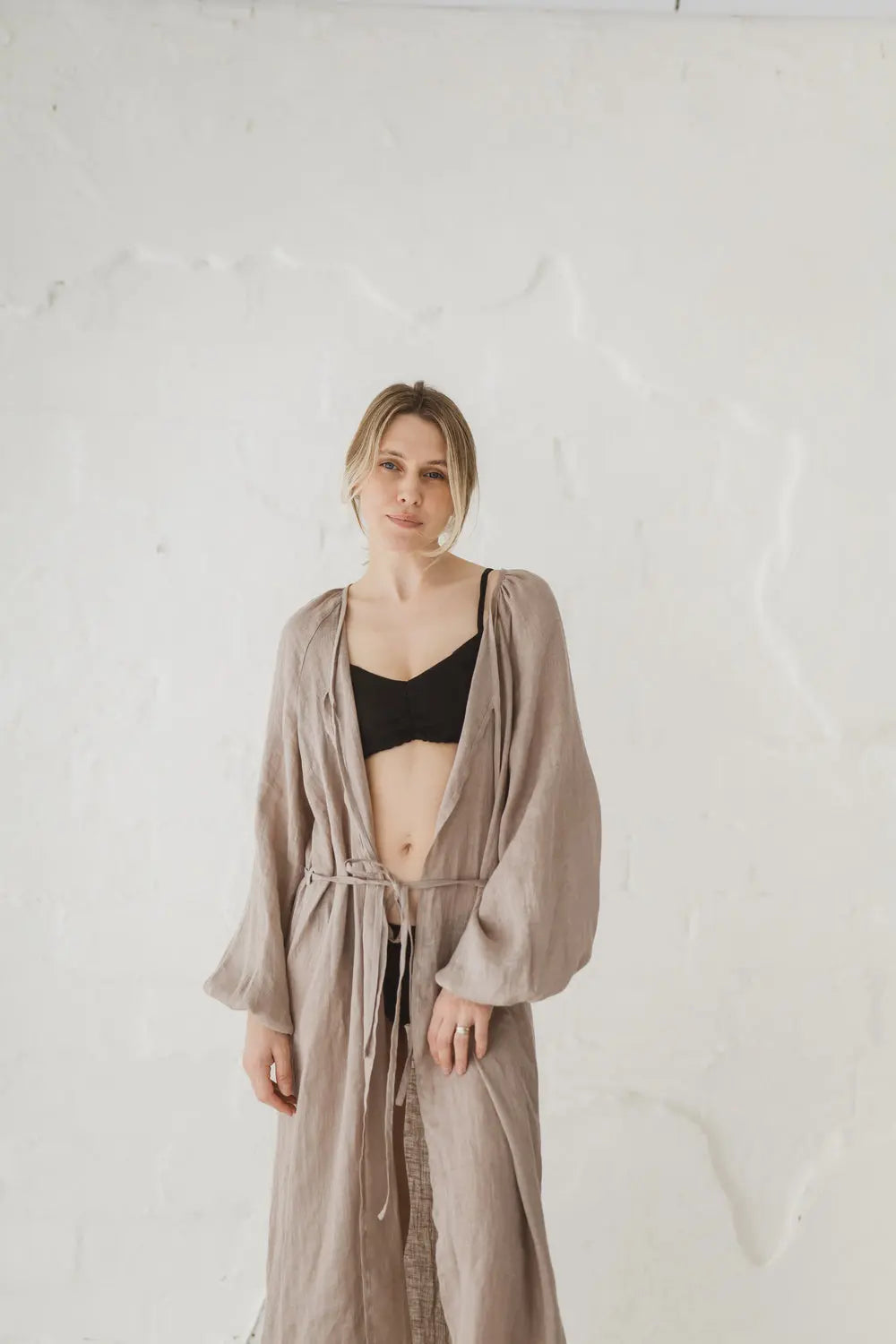 Woman wearing an open natural linen kaftan with long balloon sleeves, front view