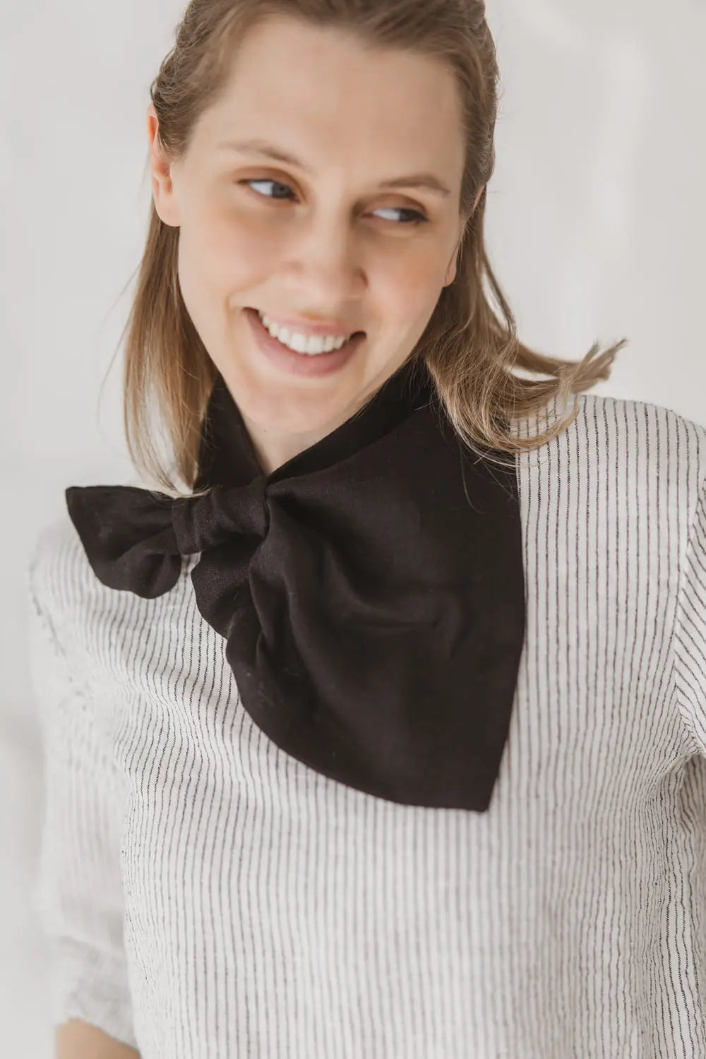 Close-up of light black linen neckerchief with sewn loop and triangle drape on linen blouse