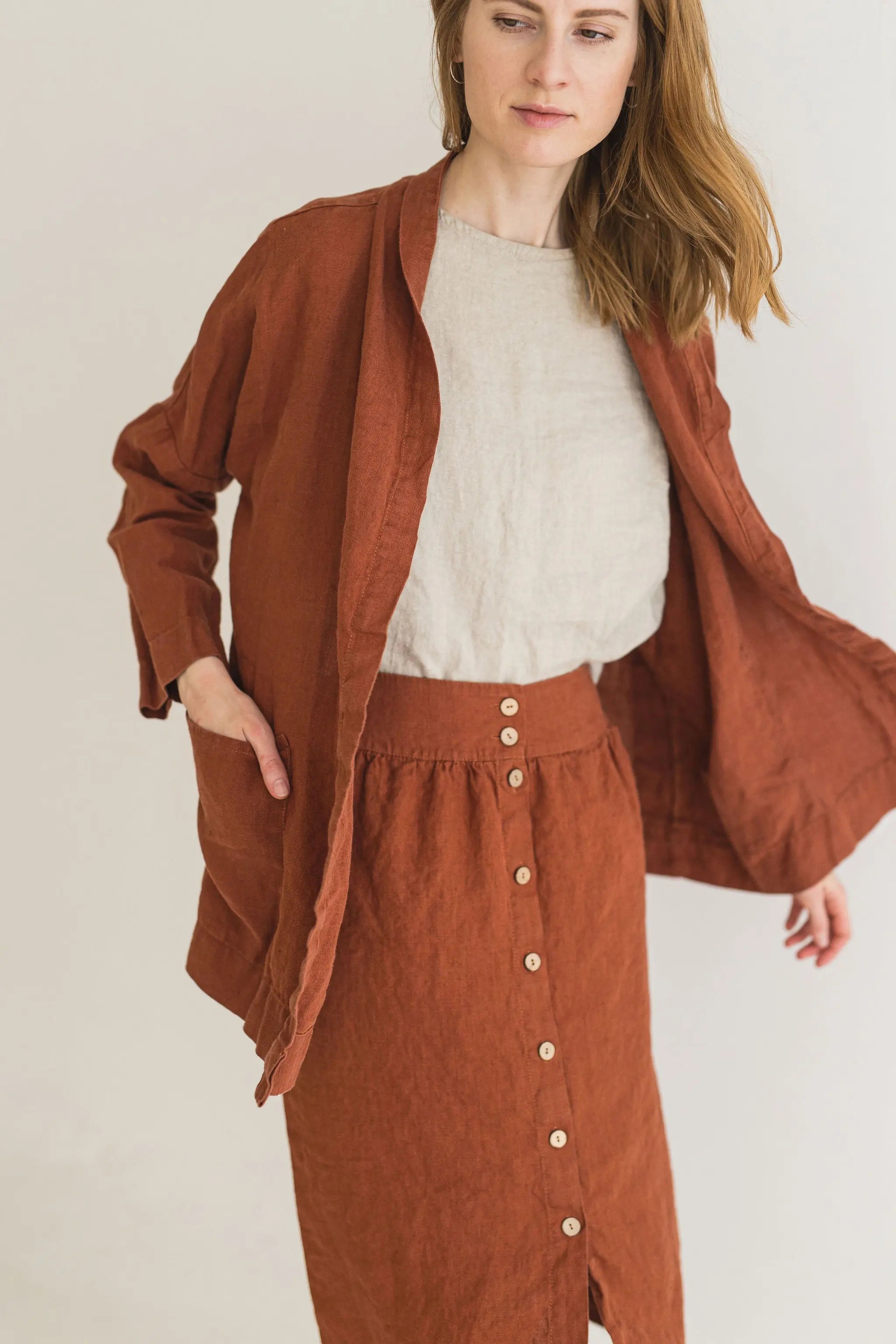 Woman wearing a brown outfit with a matching jacket and skirt on a plain background