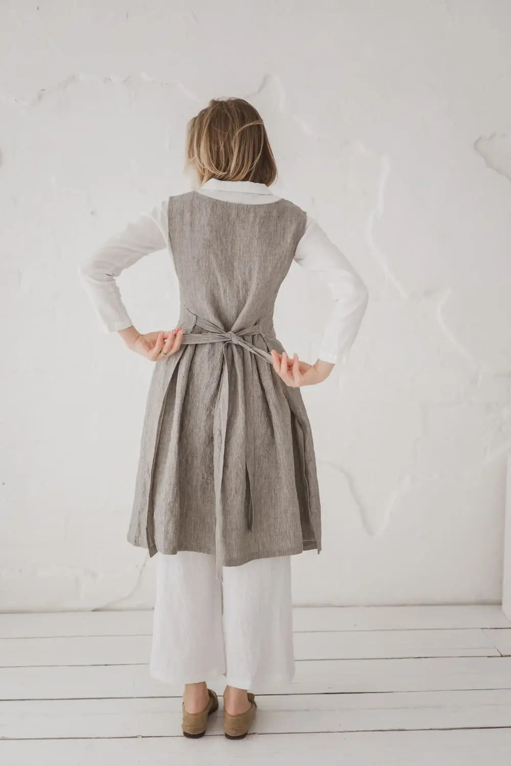 Woman tying back bow of Convertible Linen Pinafore Dress - Epic Linen
