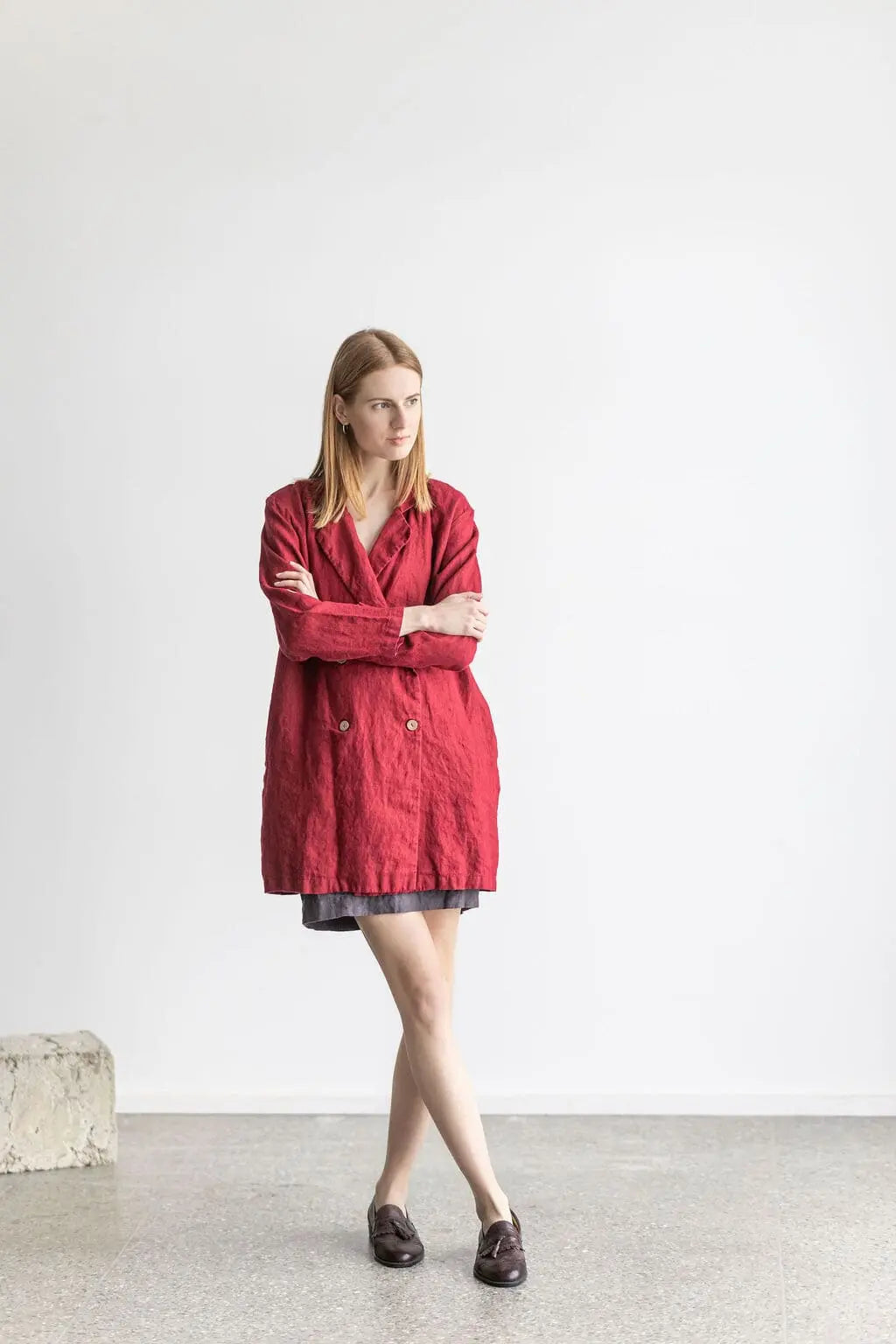 Front view of a model in a red linen jacket, crossed legs pose