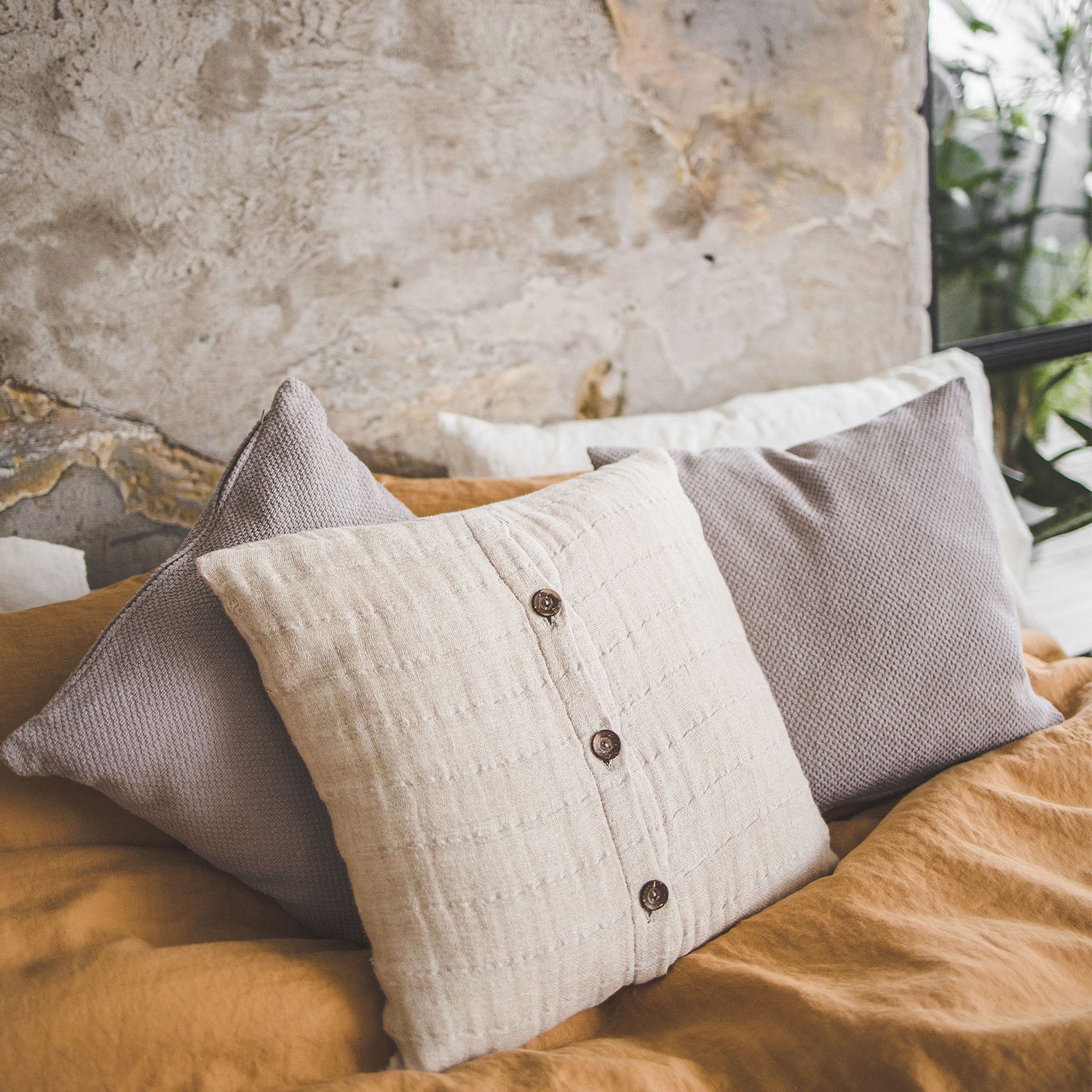 Linen and cotton cushion covers placed on a linen bedding set.