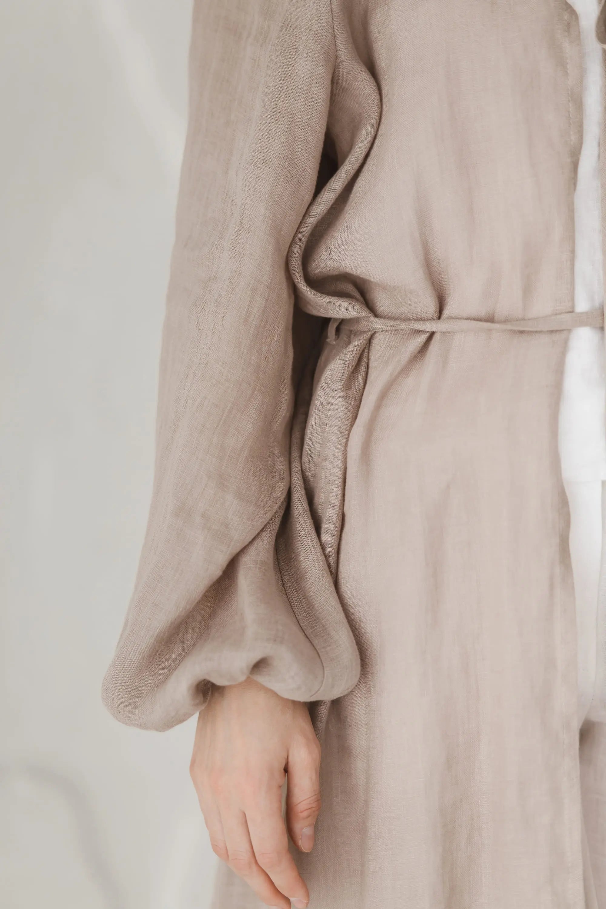 Close-up of balloon sleeve with elasticated cuff and waist tie detail on a natural linen kaftan