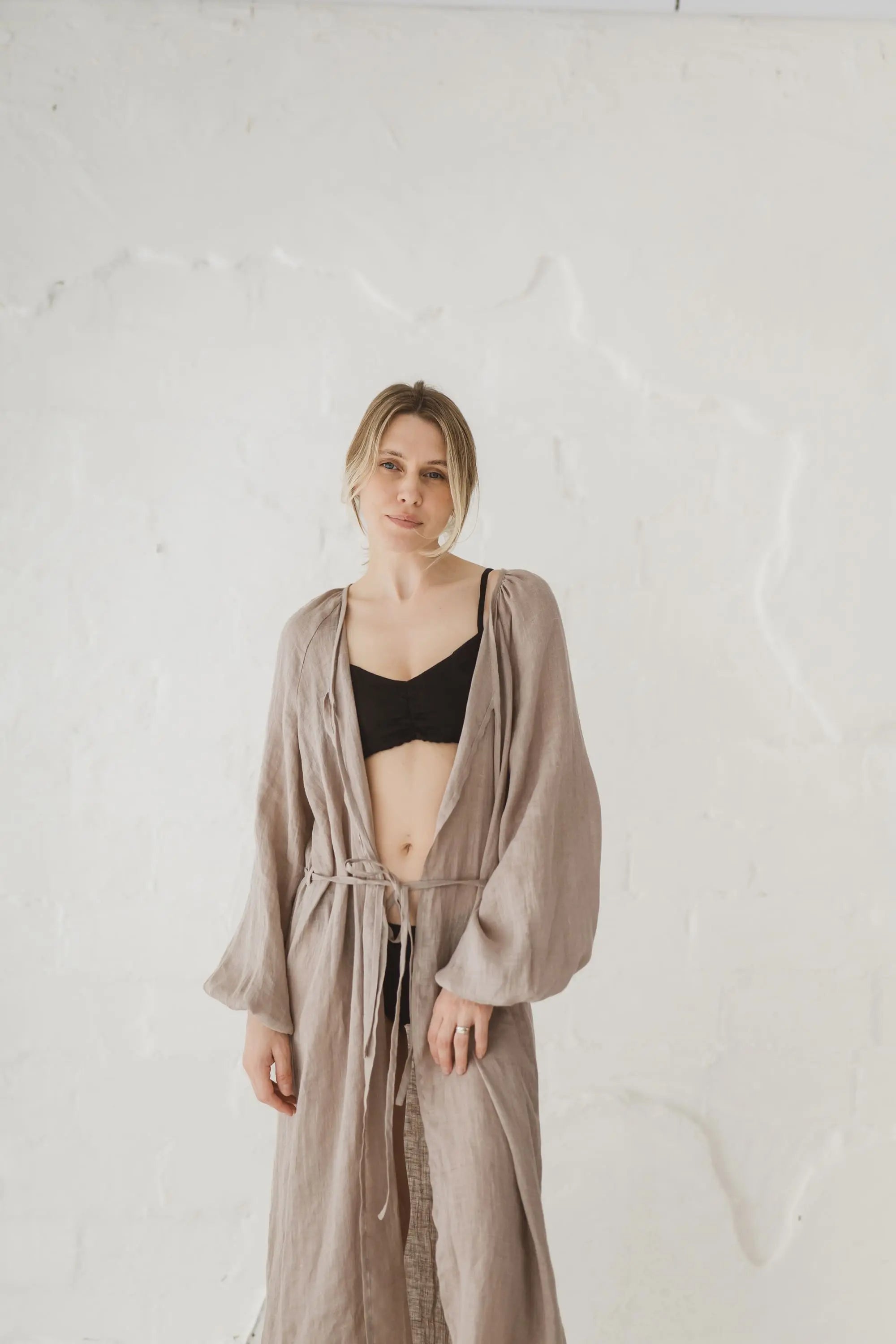 Woman wearing an open natural linen kaftan with long balloon sleeves, front view