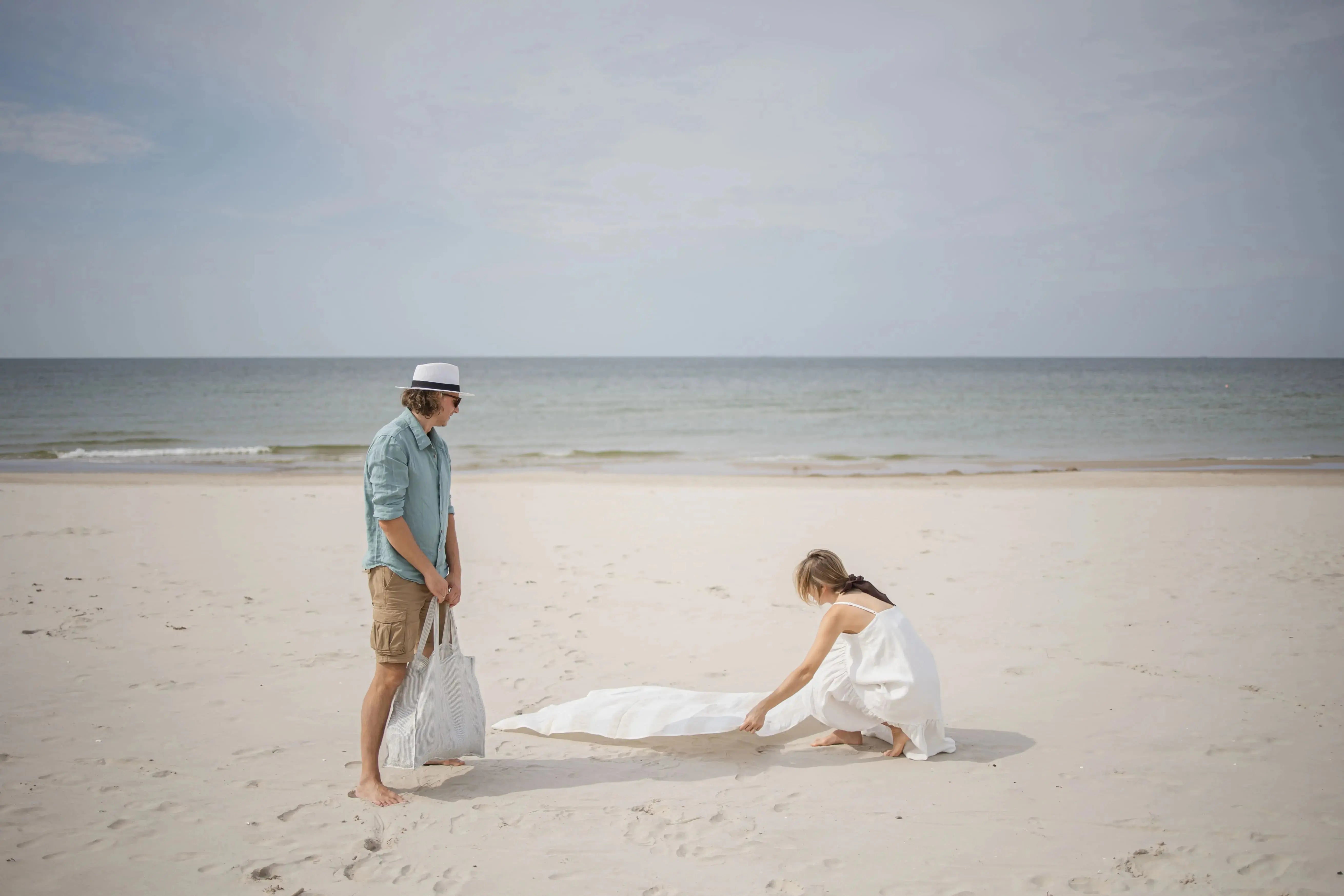 Linen Huckaback Beach Towel in white natural striped, laid out on the beach with couple
