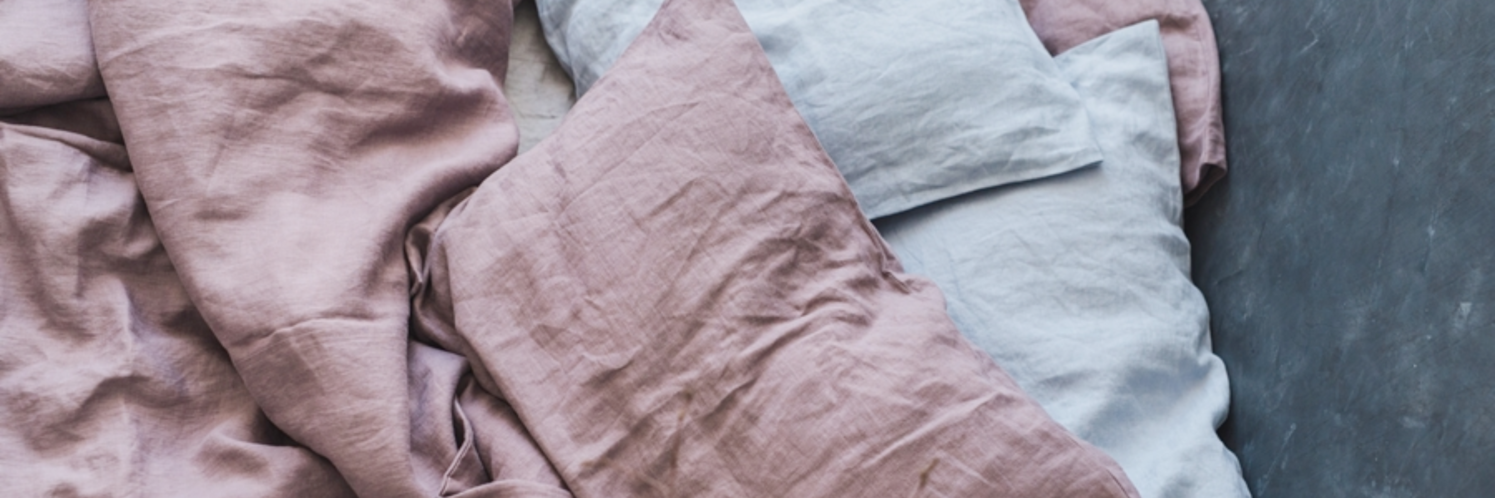 Two-color linen pillowcases laid out on a bed.